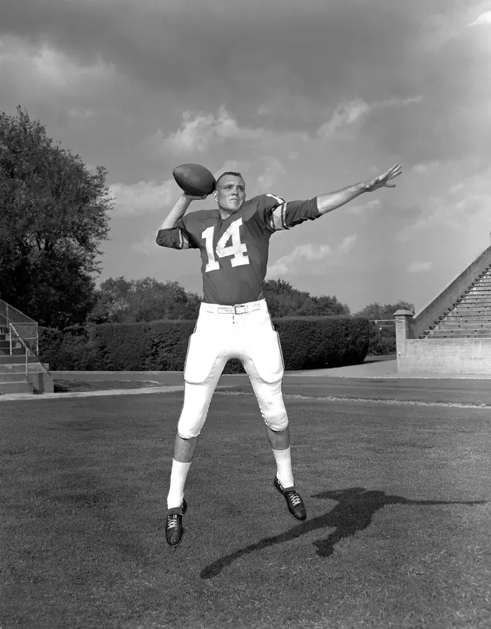 Restored photograph of Billy Guy Anderson throwing a football in jersey number 14